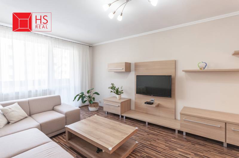 Living room of a three-room apartment with a wooden decor floor and a comfortable sofa.