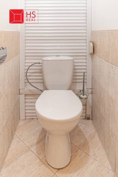 A toilet with beige tiles in a 3-room apartment, in a clean and simple design.
