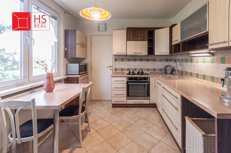 A kitchen with mosaic tiles and a table in a 3-room apartment is equipped with appliances.