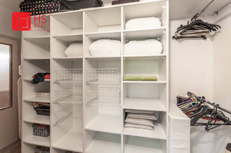 Storage space with shelves and hangers in a 3-room apartment with a wooden decor floor.