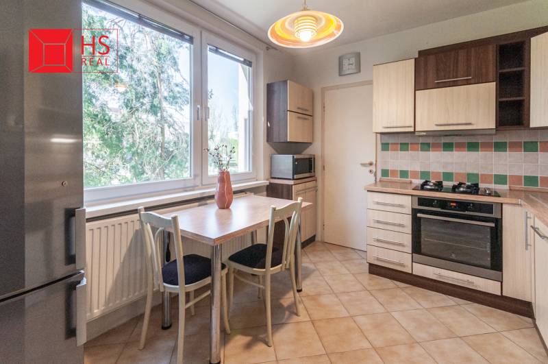 A kitchen in a 3-room apartment with a tiled wall and a floor with a wooden decor.