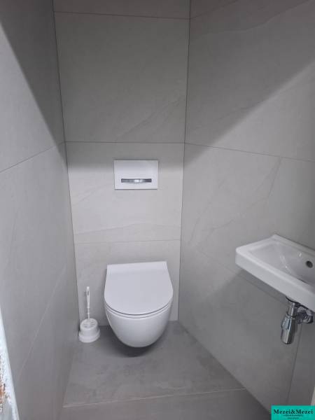 Bathroom in a family house with a toilet, sink, and white tiles.