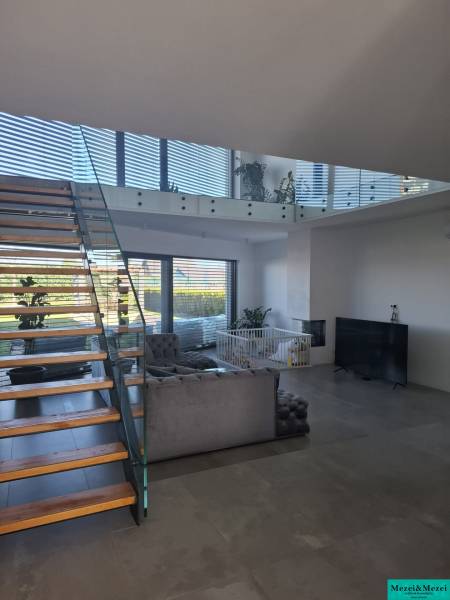Living room in a family house with a staircase and glass railings.