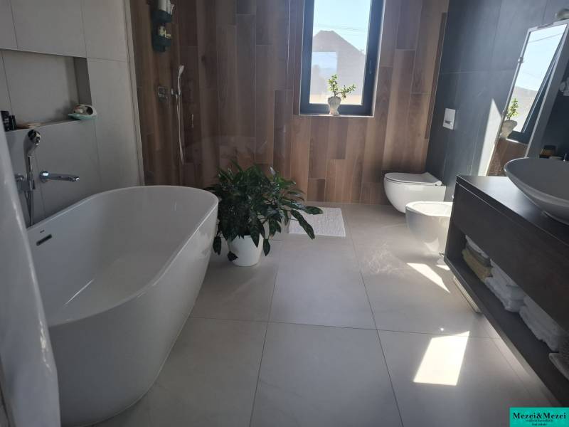 A bathroom in a family house with a bathtub, shower, and a floor with a wooden decor.