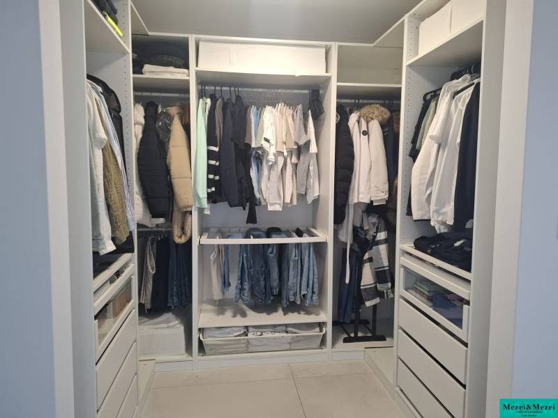 A wardrobe with clothes and dressers in a family house with a wooden decor floor.