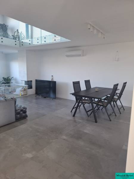 Interior of a family house with gray tiles, a dining table, and a television.