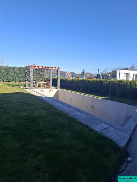 The garden of a family house in Zvončín with a pergola and an unfinished swimming pool.