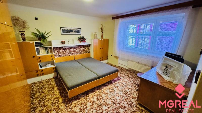 A room in a 3-room apartment with wooden decor furniture and a carpet on the floor.