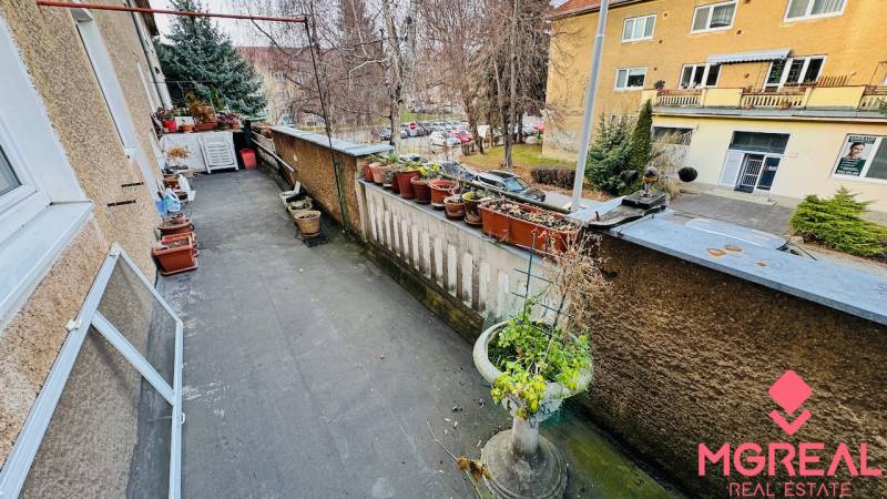 A balcony with flower pots and a view of F. Madvu Street in Prievidza offers a peaceful environment.