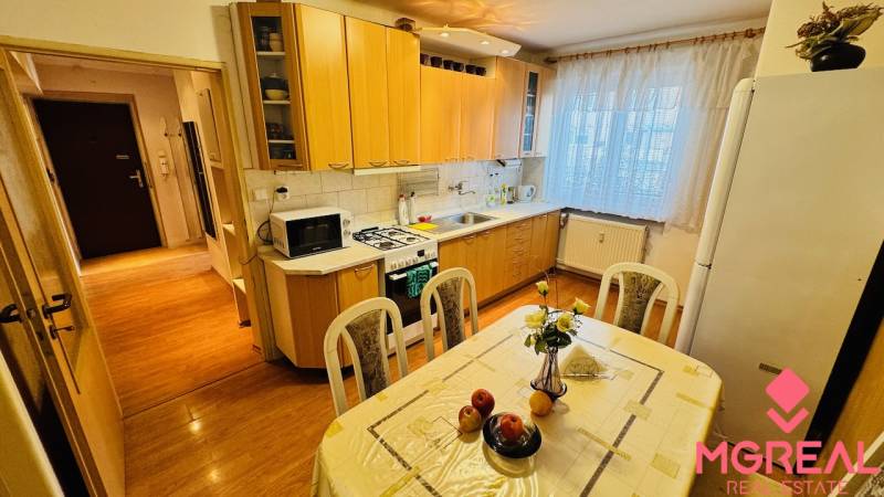 A kitchen in a 3-room apartment with a wooden decor floor and a dining table.