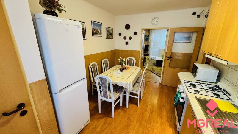 A kitchen in a 3-room apartment with a dining table and a wooden decor floor.