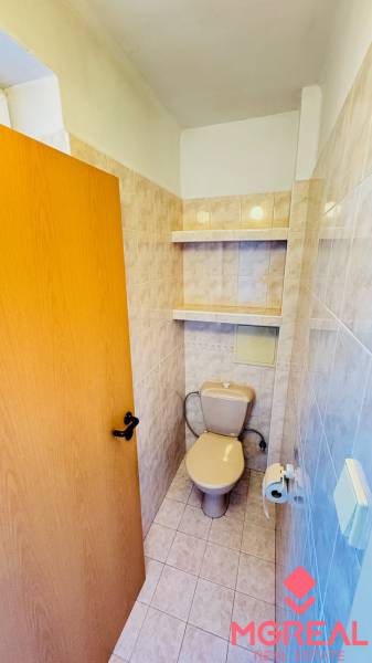 A toilet with ceramic tiles and storage shelves, part of a 3-room apartment.