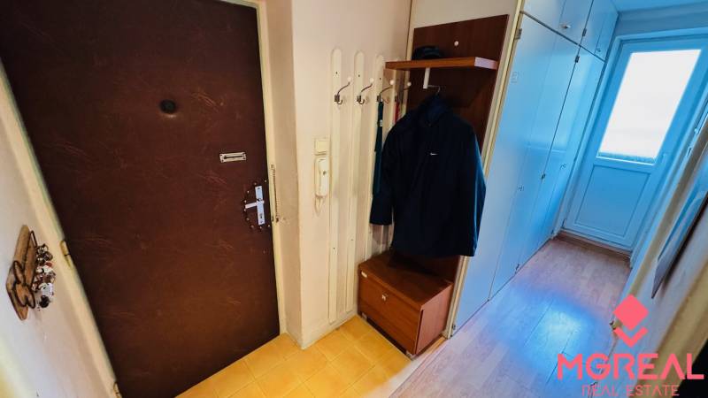 Entrance hall with a coat rack, cabinet, and floor with wooden decor in a 3-room apartment.