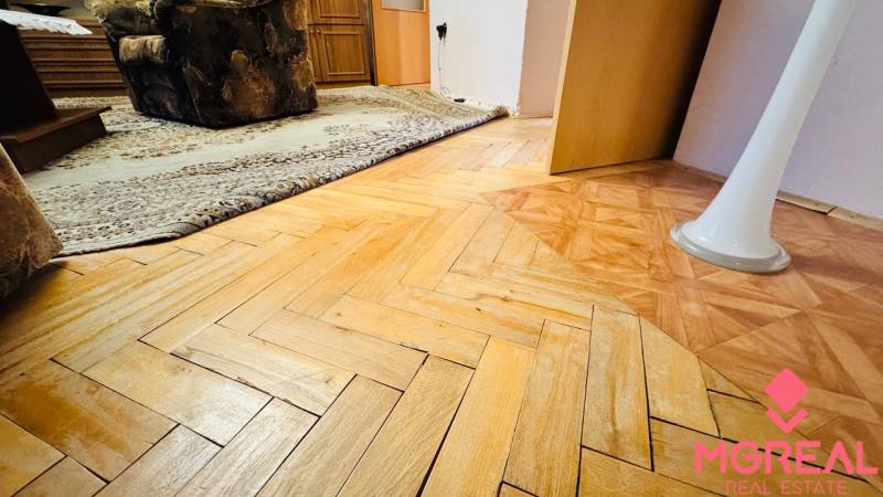 A floor with a wood decor in a 3-room apartment, carpet, and furniture in the interior.
