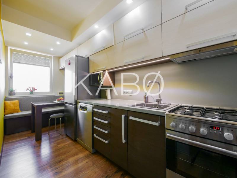 A kitchen in a 3-room apartment with a wooden decor floor and corner seating.