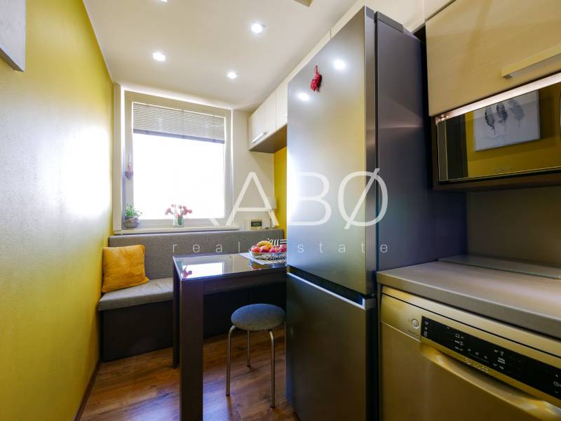 A kitchen in a 3-room apartment with a wooden decor floor, a dining area with a bench.