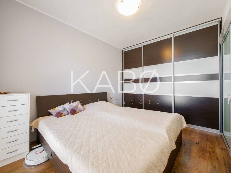 A bedroom in a three-room apartment with a wooden decor floor and a built-in wardrobe.