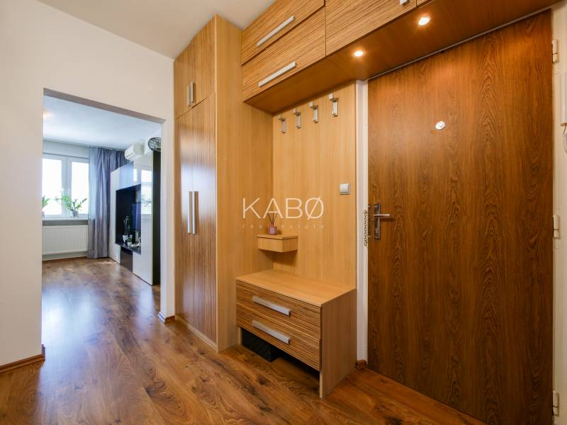 Interior of a 3-room apartment with a hallway, wooden cabinets, and flooring with a wood decor.