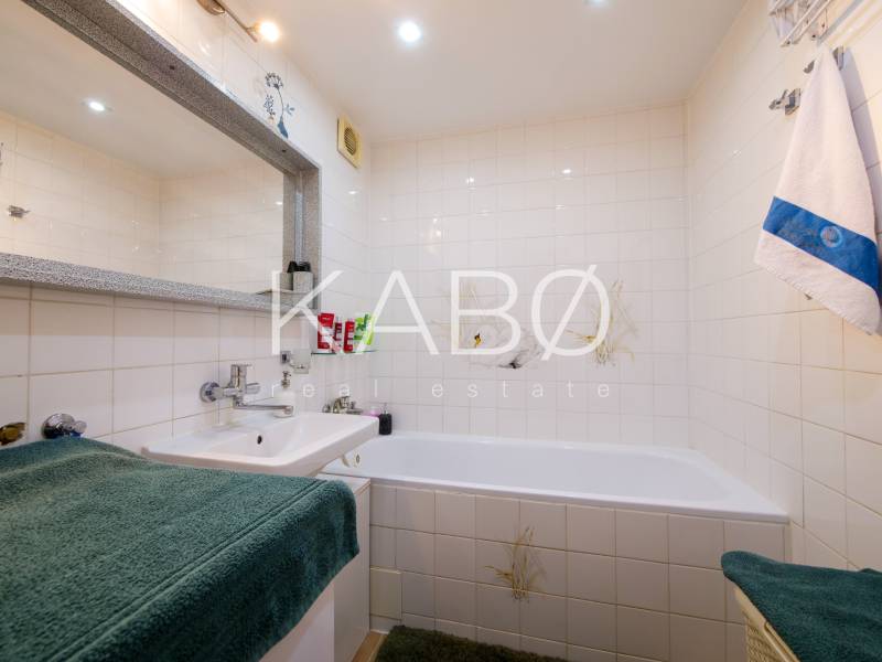 Bathroom in a 3-room apartment with a bathtub, sink, and white tiles.