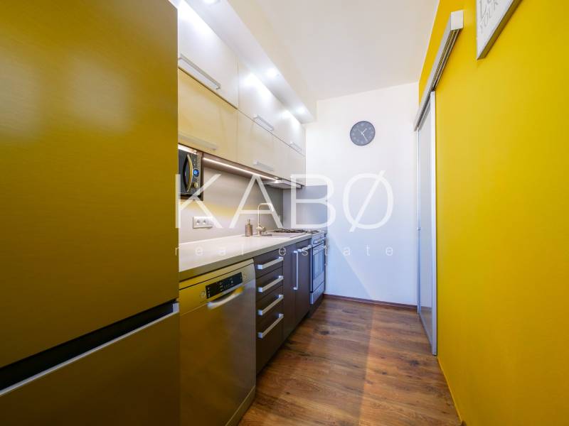 A kitchen in a 3-room apartment with a colored wall and a floor with a wood decor.