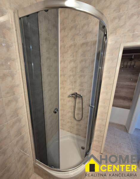A shower corner with ceramic tiles in a studio apartment.