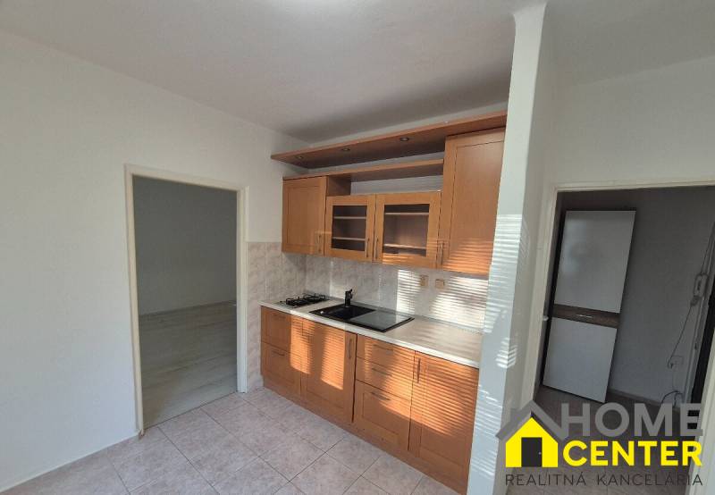 A kitchen unit with ceramic tiles in a studio apartment with a wooden decor floor.