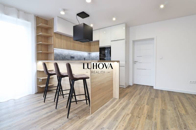 A kitchen in a 3-room apartment with a bar counter and a wooden decor floor.
