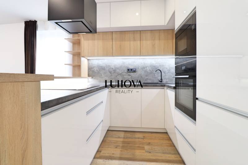 A kitchen in a 3-room apartment with white cabinets and a wood-patterned floor.