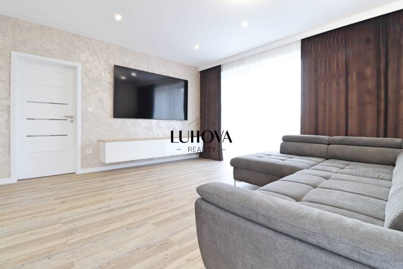 Living room in a three-room apartment with a sofa and wooden decor flooring.