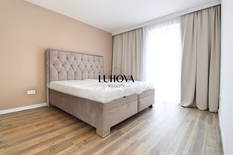 A bedroom with a bed and a wooden decor floor in a three-room apartment.