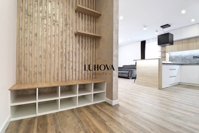 Interior of a 3-room apartment with wood-patterned flooring, kitchen, and living area.