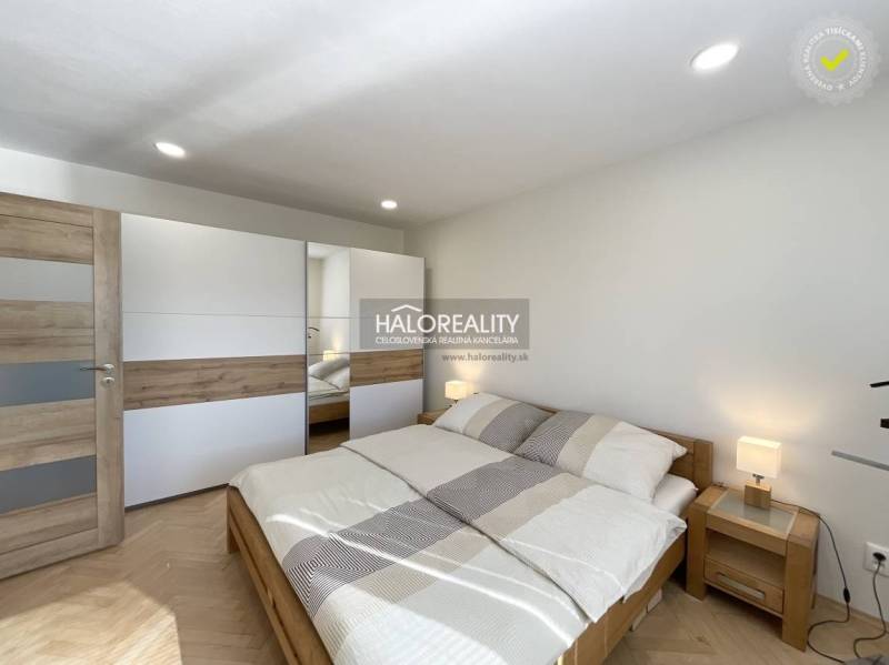 A bedroom with wood-patterned flooring in a studio apartment, light bed and wardrobe.