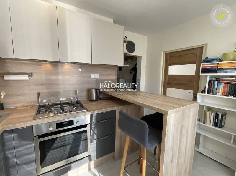 A kitchen in a studio apartment with a kitchen counter and appliances.