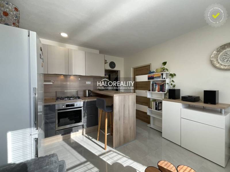 A kitchen in a studio apartment with a bright interior and a seating counter.