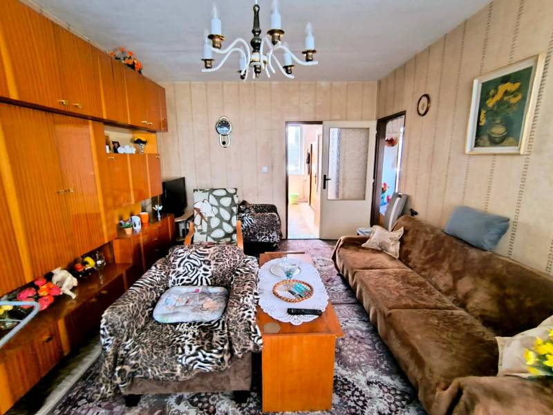 Living room in a 3-room apartment with wooden decor, carpet, and sofas.