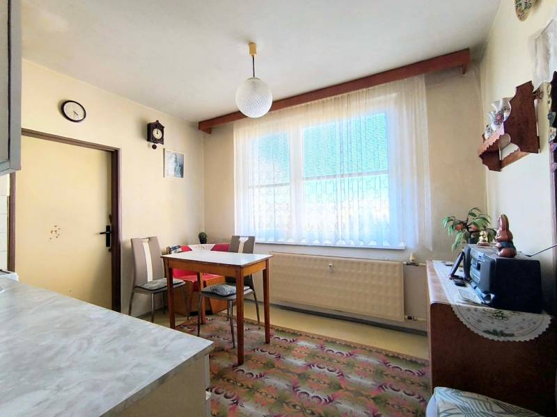 A dining room with simple furniture in a 3-room apartment, a floor with a decorative carpet.