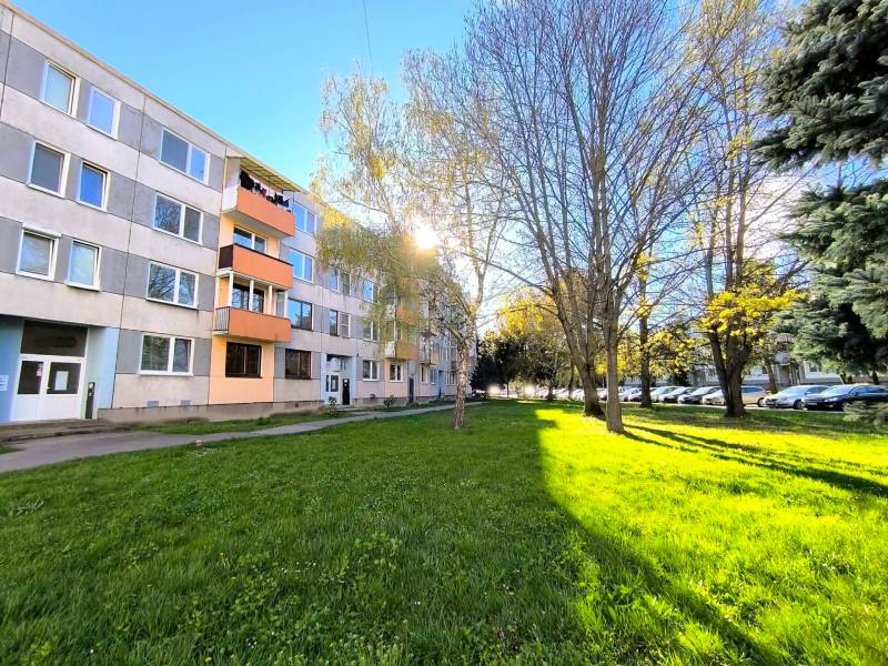 The apartment building on Veľká Okružná in Partizánske surrounded by greenery and parked cars.