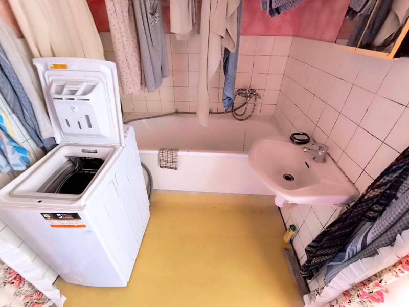 Bathroom with a sink, bathtub, and washing machine in a 3-room apartment.