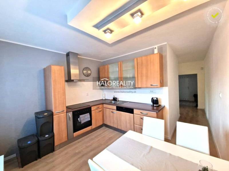 The kitchen in a 3-room apartment with a wooden decor floor, a dining table, and appliances.