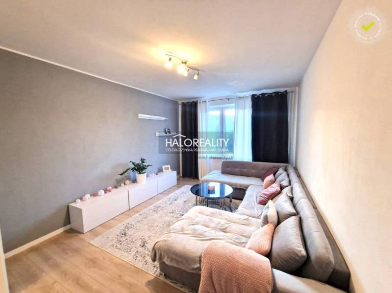 Living room in a three-room apartment with a wooden decor floor and a corner sofa.