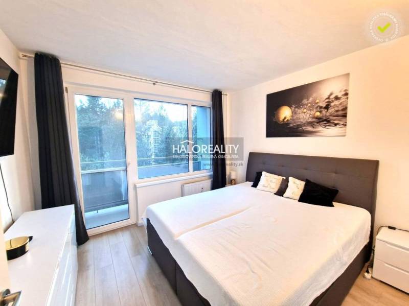 A bedroom in a 3-room apartment with a large window and a bed; floor with wooden decor.
