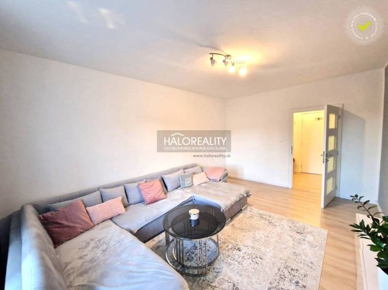 Living room in a 3-room apartment with a large corner sofa and a floor with a wooden decor.