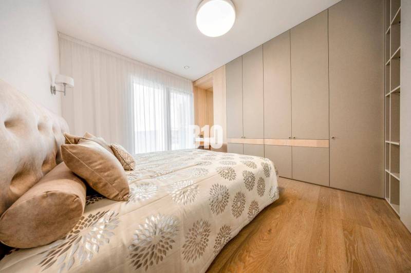 Bedroom in a 3-room apartment with a bed, built-in wardrobe, and wooden decor flooring.