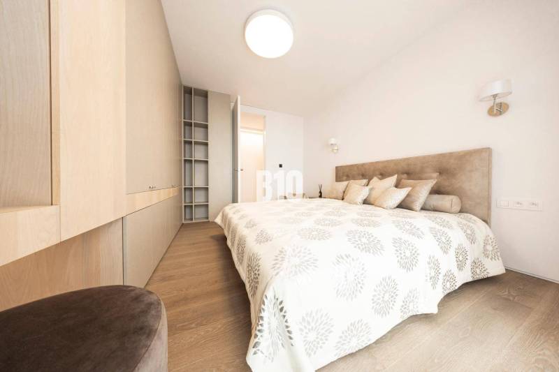 A bright bedroom with wood-patterned flooring and built-in wardrobes in a 3-room apartment.