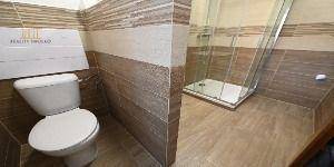 Bathroom in a 2-room apartment with a toilet and tiles with a wooden decor.