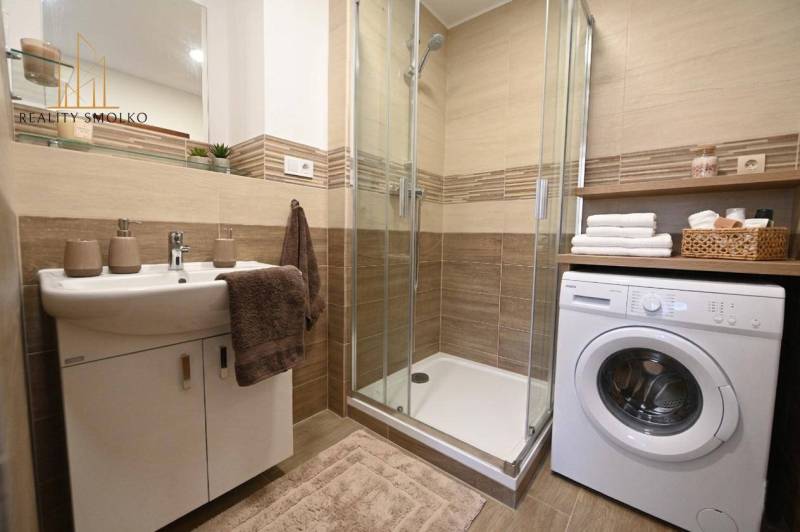 Bathroom in a 2-room apartment with a washing machine and a shower, floor with wooden decor.