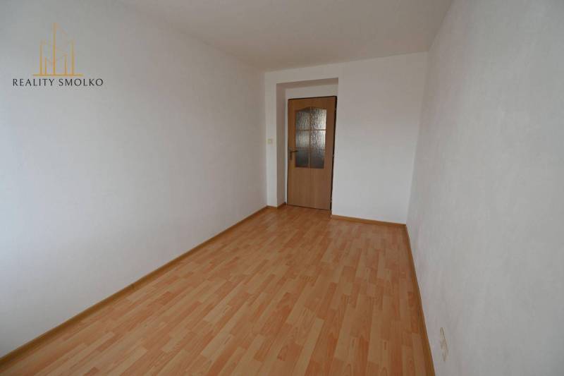 A room in a 2-room apartment with a wooden decor floor and white walls.