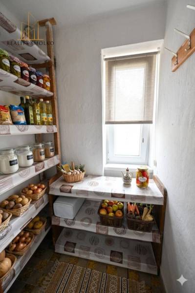 Pantry with shelves, fruits, vegetables, and groceries in a 2-room apartment, light coming through the window.