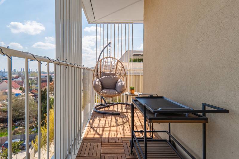 A balcony of a 3-room apartment in Bratislava-Ružinov with a swing and a view of the city.