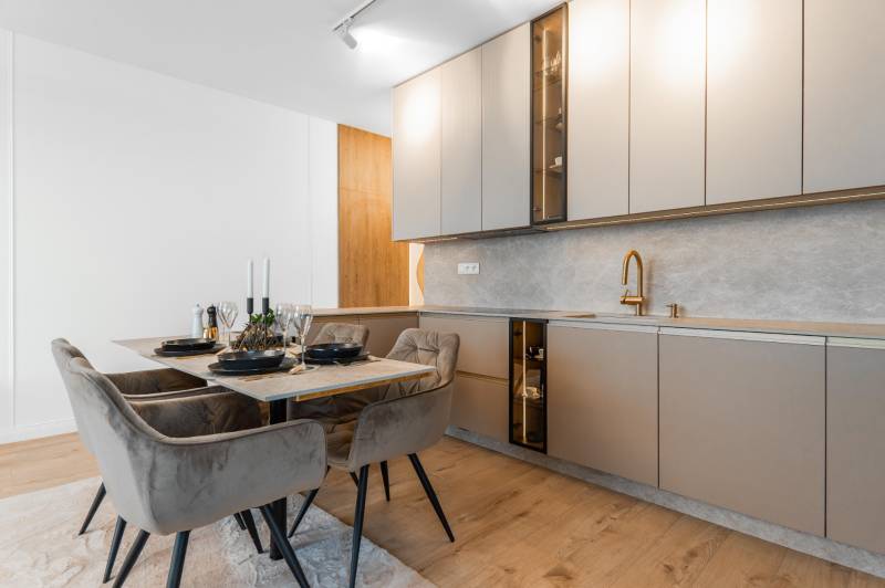 A kitchen in a 3-room apartment with a dining table and a floor with a wooden decor.